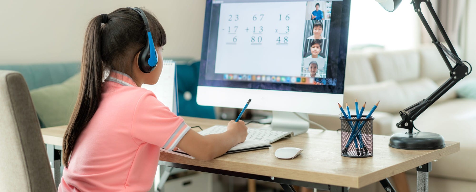 A girl wearing headphones is focused on her computer, engaged in her work with concentration and determination.