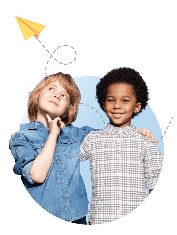 Two children stand side by side, smiling, while holding a paper airplane between them.